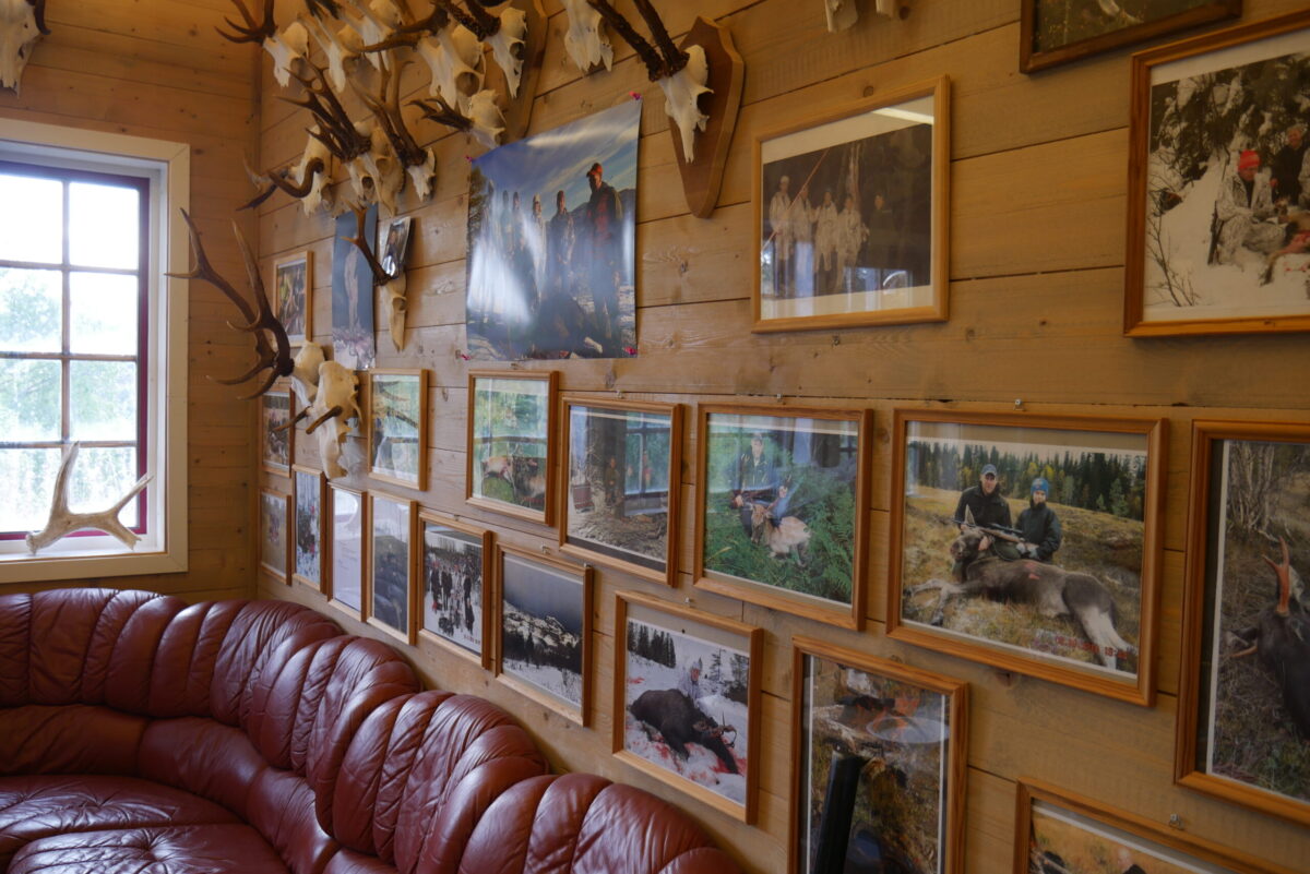 Stue i jakthytta med foto og gevir på veggene.