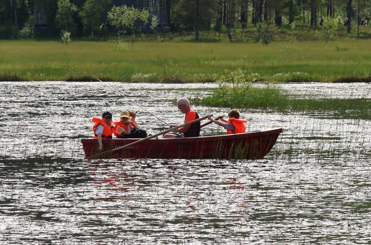 Barn og en voksen ute i en båt på et lite vann