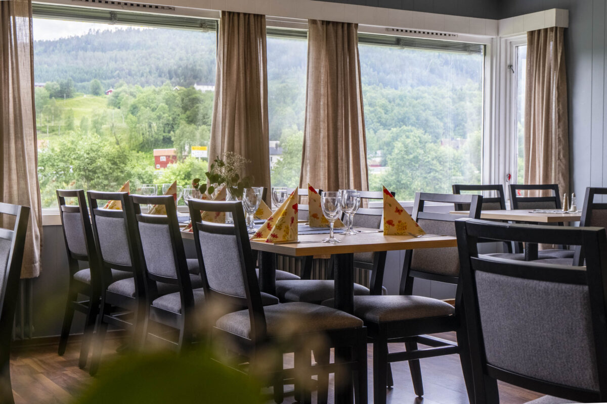 Spisesal med dekte bord og store vinduer